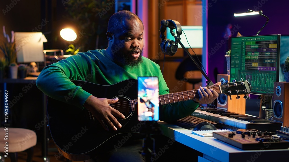 Fototapete Professional composer teaching guitar lessons online on master class, recording himself playing acoustic instrument accords and explaining notes for tutorial. Young musician making vlogs. Camera A.