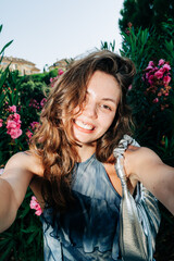 Young caucasian female taking selfie in floral garden with natural light