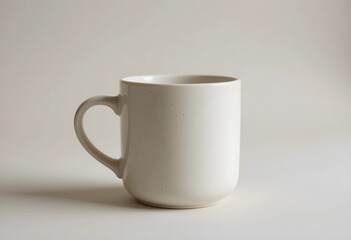 A ceramic mug with a smooth handle on a neutral surface. Soft lighting highlights its clean design and subtle texture. A simple, minimalist composition emphasizing warmth and everyday use.