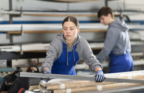 During work process, girl employee produces blanks for repairs and interior decoration. She carries out installation work, products for renovation of residential premises made of glass and plastic.