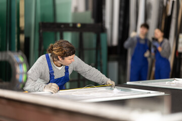 Man employee works on cutting table, measuring source material with tape measure. She finds out...