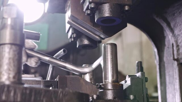Male worker's hands control hydraulic machine to bend steel pipes to the desired size and shape for use as mechanical spare parts in a parts manufacturing 