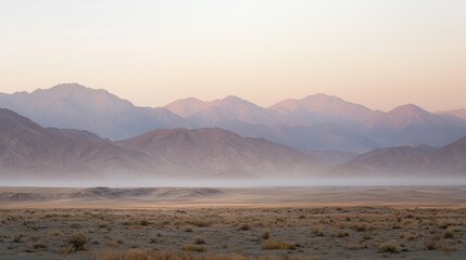 Fototapeta premium Hazy sunrise over vast desert landscape and distant mountains.
