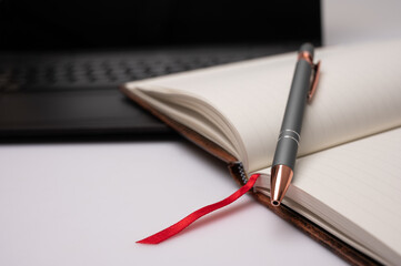 pen on notebook with a computer