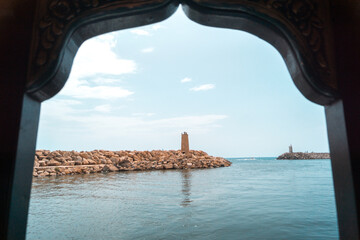 Peaceful Harbor Vista with Lighthouse Through Ornate Frame Against Clear Sky