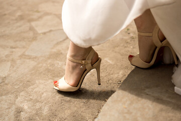 Elegant Beige High-Heeled Sandals with Red Pedicure on Stone Surface