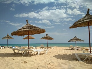 Tropical Paradise Beach with Thatched Umbrellas and White Loungers on Turquoise Coast