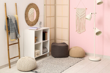 Interior of modern living room with shelving unit, folding screen and poufs