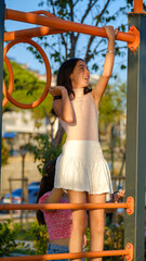 A moment of a dark-skinned teenage girl having fun with toys in a children's park on a sunny summer...