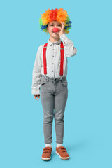 Funny little boy in clown wig and nose on blue background. April Fools Day celebration