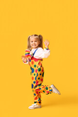 Smiling little girl in clown costume on yellow background