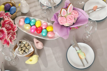 Festive table setting with flowers, Easter cakes and painted eggs