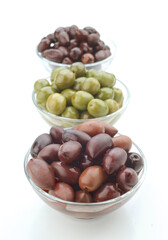 Various types of olives displayed in glass bowls for culinary use and decoration