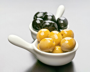 Varied olives in white serving dishes arranged on a dark surface