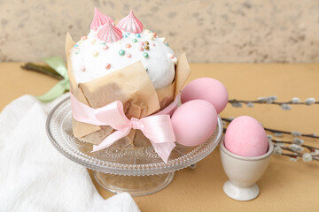 Stand with tasty Easter cake, eggs and willow branches on brown table