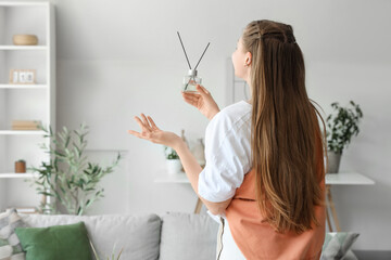 Beautiful young woman with aroma diffuser at home