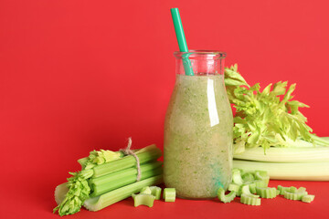 Bottle of celery juice with chopped and whole celery on red background