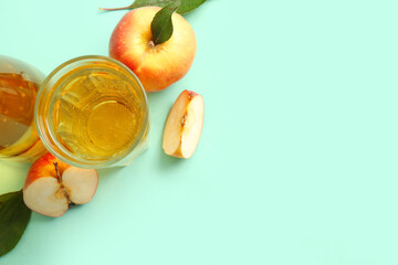 Glass of fresh apple cider and fruits on green background