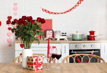 Table with wine, roses and gift box in festive kitchen. Valentine's Day celebration