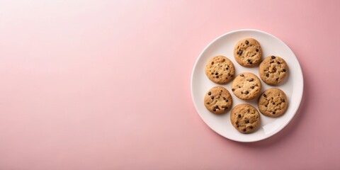 Obraz premium A plate of freshly baked chocolate chip cookies on a pink background, perfect for a sweet treat or a delightful snack