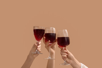 Female hands with glasses of red wine on beige background