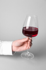 Female hand with glass of red wine on white background