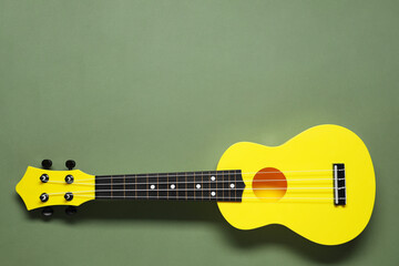 One ukulele on olive background, top view. Space for text