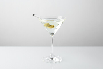 Martini cocktail with olives in glass on light table