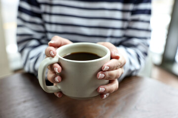 Woman having coffee break at wooden table in cafe, closeup