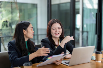 Colleagues discussing financial strategies with documents and a laptop in a collaborative environment.