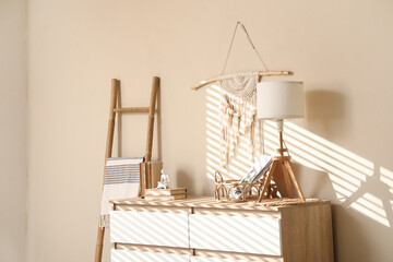 Interior of living room with stepladder and chest of drawers near beige wall