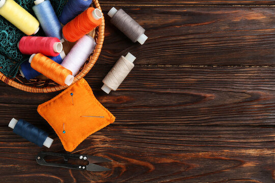 Different sewing supplies on wooden background, flat lay. Space for text