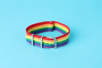 One wristband in LGBT colors on light blue background, closeup