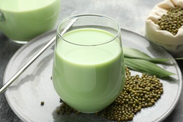 Fresh mung bean juice in glass, seeds and green leaves on table, closeup