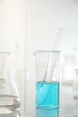Laboratory glassware on mirror surface against light background