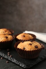 Delicious muffin with chocolate chips on black table, closeup