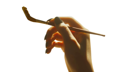 Woman artist hand holding paintbrush with gold paint on transparent background