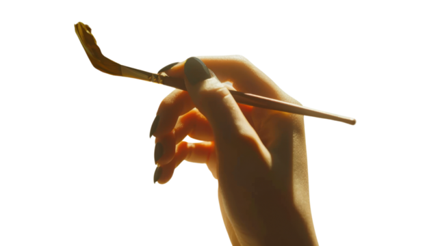 Woman artist hand holding paintbrush with gold paint on transparent background