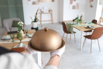 Male waiter with cloche in restaurant, closeup
