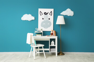 Interior of children's room with floor lamp, desk and chair near blue wall