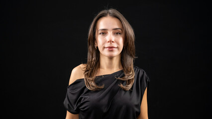 A chest-up headshot of a young, brown-haired woman taken in a studio setting with a black background