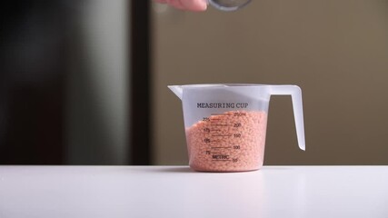 Chef pouring red lentils into measuring cup for precise cooking - Powered by Adobe