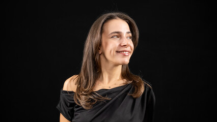 A chest-up headshot of a young, brown-haired woman taken in a studio setting with a black background