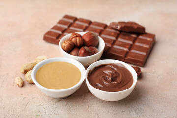 Bowls of sweet chocolate spread and nut butter on beige background