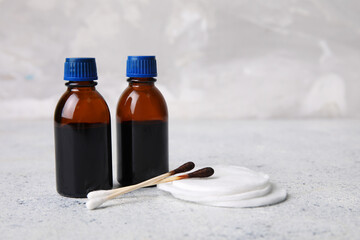 Bottles with iodine, cotton swabs and pads on grey grunge background, closeup