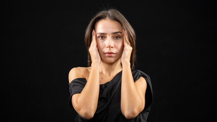A chest-up headshot of a young, brown-haired woman taken in a studio setting with a black background