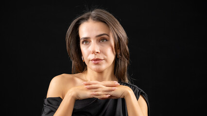A chest-up headshot of a young, brown-haired woman taken in a studio setting with a black background