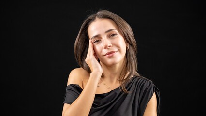 A chest-up headshot of a young, brown-haired woman taken in a studio setting with a black background
