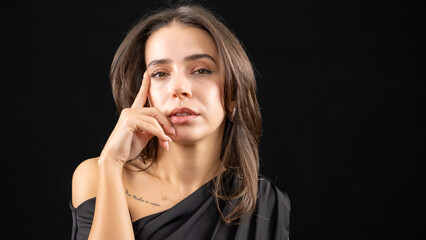 A chest-up headshot of a young, brown-haired woman taken in a studio setting with a black background