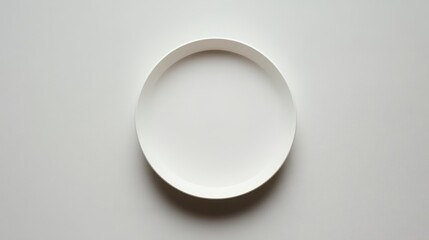 A minimalistic scene featuring a white plate with a subtle rim, elegantly placed on a matching white surface, emphasizing simplicity and cleanliness.
